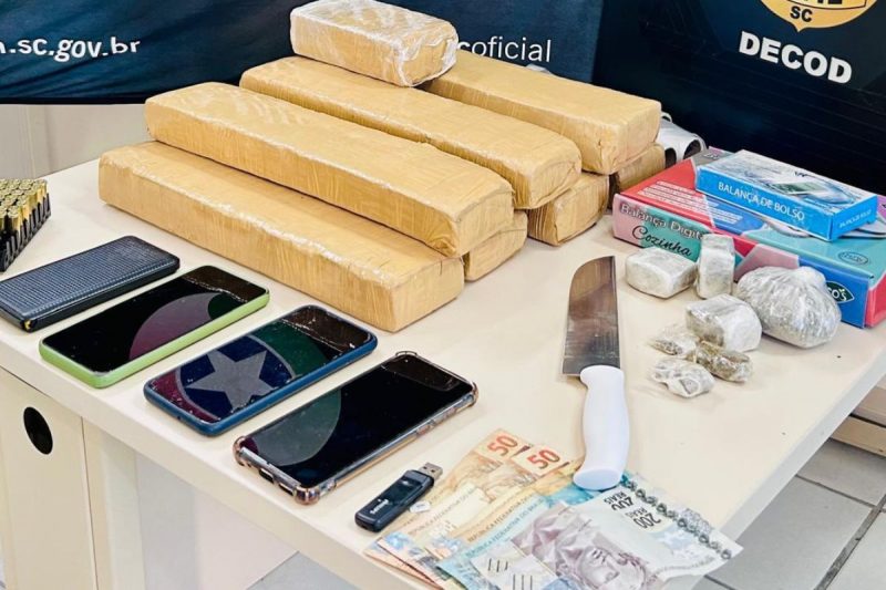 Mesa com barras de drogas, celulares, faca e dinheiro