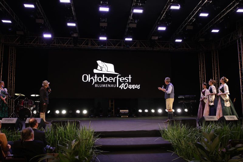 Celebração de 100 dias para a Oktoberfest Blumenau, com banner dos 40 anos logo atrás