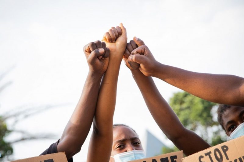 Pessoas negras segurando cartazes com manifesto contra injúria racial