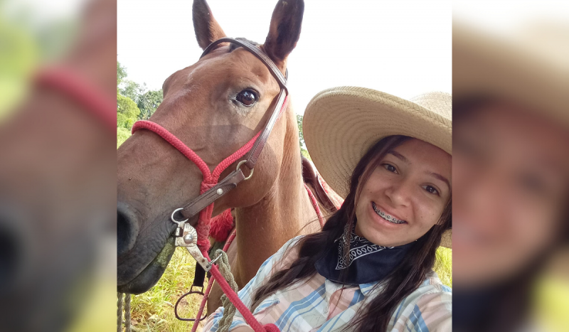 Jovem que morreu após ter perna decepada - Menina sorrindo usando aparelho ortodôntico e chapéu de palha posa usando camisa quadriculada e ao lado de cavalo