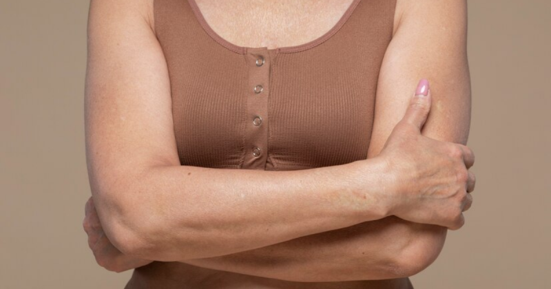 Mulher com os braços cruzados, vestindo uma roupa marrom