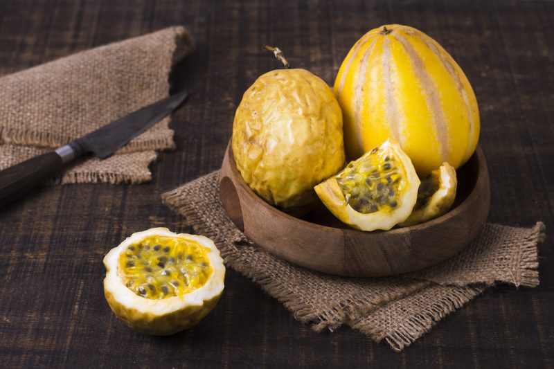 Maracujás em cima de uma mesa com uma faca ao lado