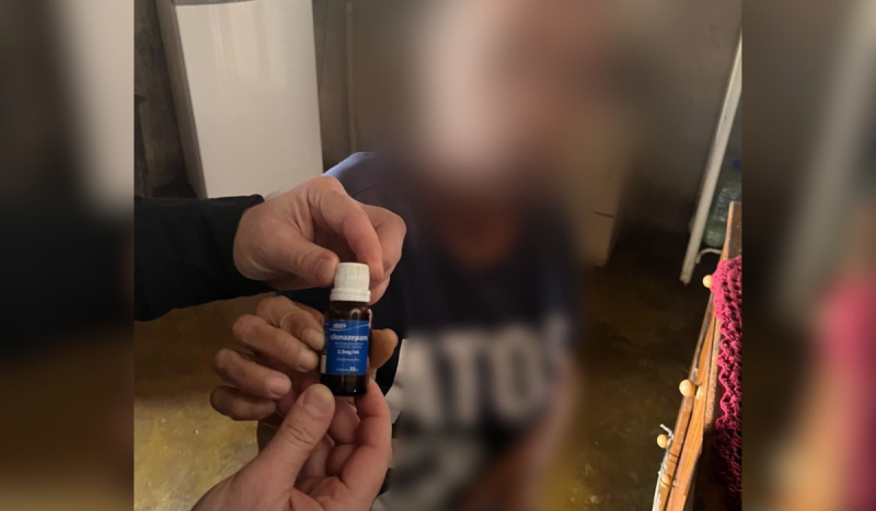 Mãos de homem branco seguram vidro pequeno da susbtância clonazepam