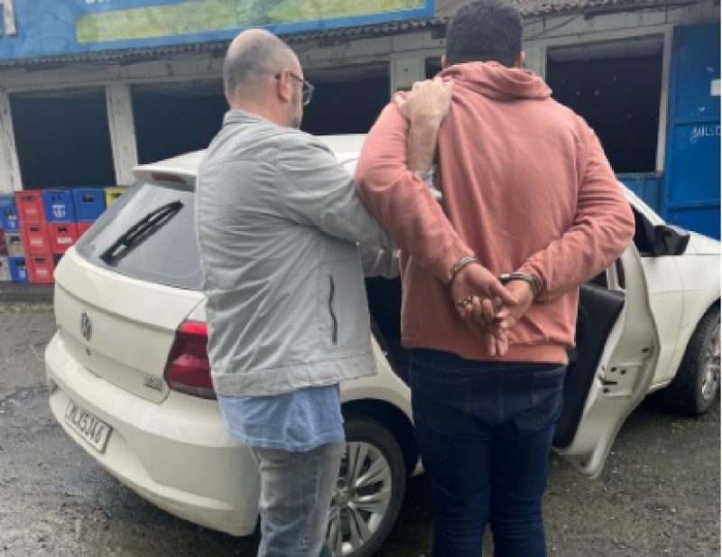 Condenado por estupro de vulnerável sendo colocado em carro por policial 