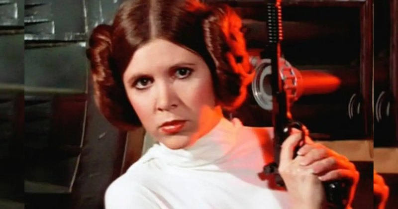 Carrie Fisher interpretando Princesa Leia com arma na mão