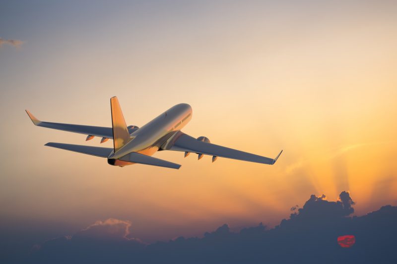 Avião decolando com céu alaranjado