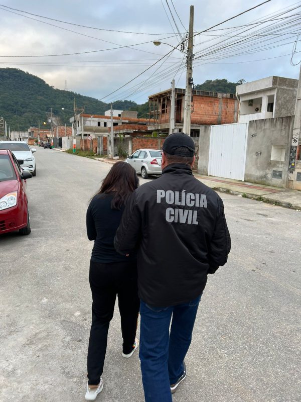 Mulher suspeita de auxiliar no roubo de armas sendo levada por policial civil