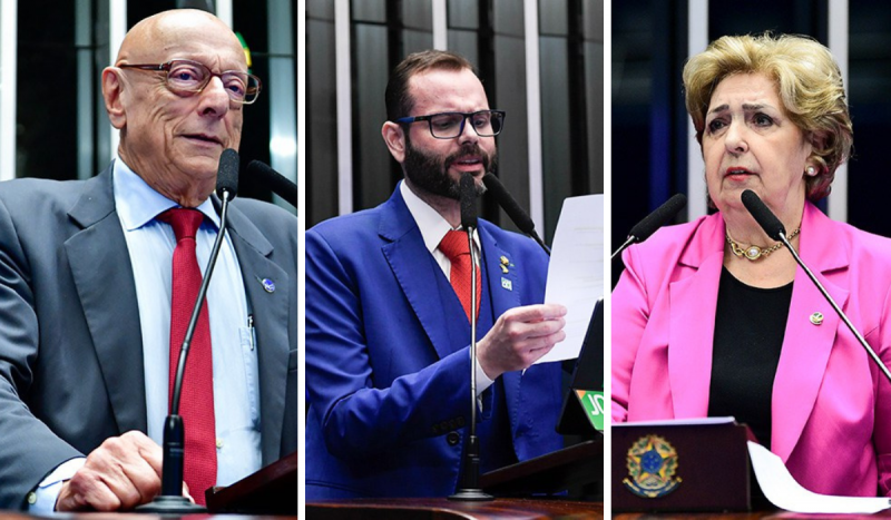 Senadores de SC: Esperidião Amin (à esquerda) - homem idoso, branco, careca, usa óculos de armação marrom, usa gravata vermelha, camisa social branca e terno cinza; Jorge Seiff (ao centro) - homem branco, com barba, bigode e cavanhaque usa gravata vermelha, terno azul e lê papel em frente a microfone; e Ivete da Silveira (à direita) - mulher, idosa, branca e loira, usa blusa preta e terno rosa por cima, fala em frente a microfone