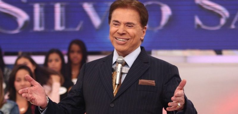 foto mostra Silvio Santos sorrindo de braços abertos