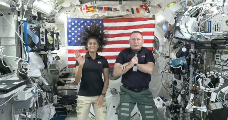 Astronautas presos no espaço, com bandeira dos EUA por trás