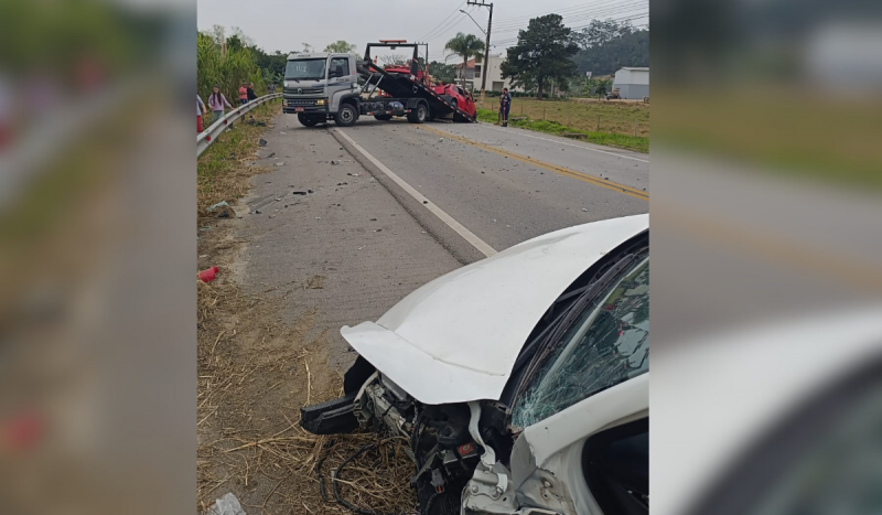 Caminhão guincho tirando carro vermelho de pista após acidente em rodovia de SC