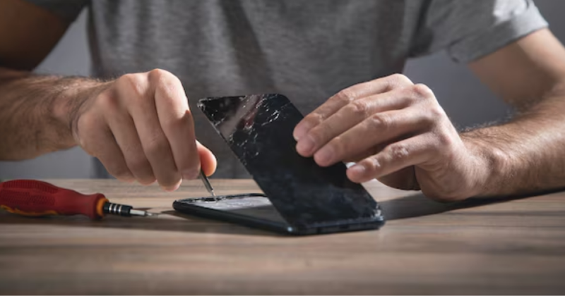 Homem consertando celular com chave de fenda