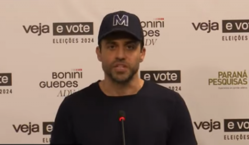 Pablo Marçal em debate nesta segunda-feira (19) - homem branco usando camiseta e boné pretos falando em púlpito