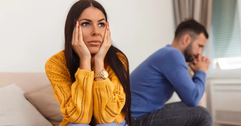 Mulher com mãos no rosto e homem por trás chateado
