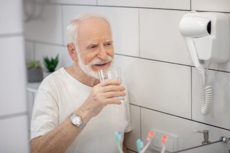 Senhor bebendo água em banheiro