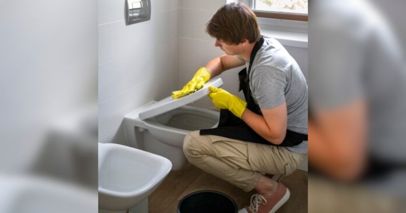 Homem limpando vaso sanitário com luvas