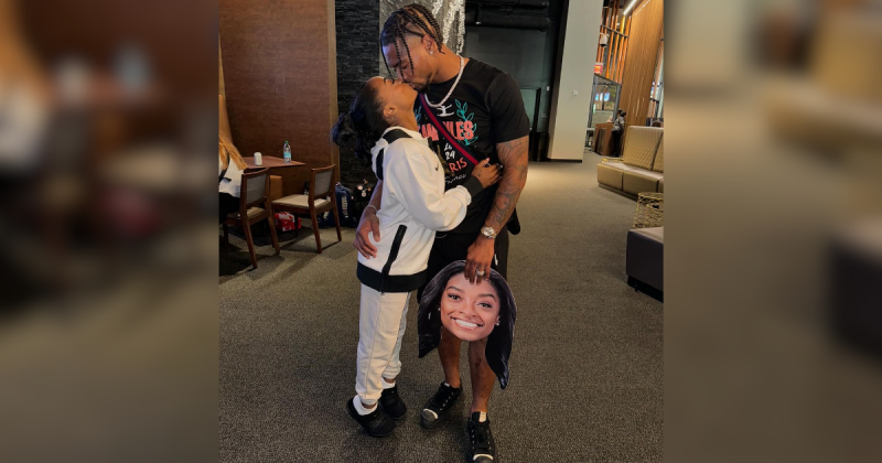Simone Biles beijando marido enquanto ele segura máscara de esposa na mão