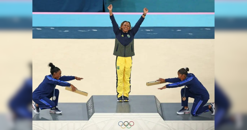Rebeca Andrade, Simone Biles e Jordan Rebeca Andrade com as mãos para cima e Simone Biles e Jordan agachadas em pódio