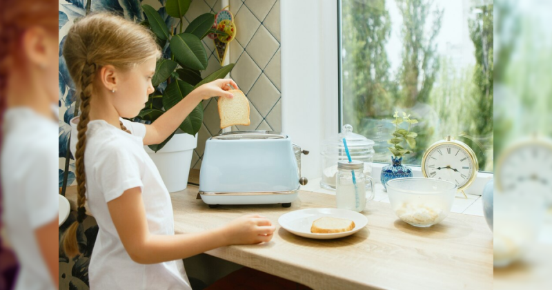 Menina colocando pão em torradeira