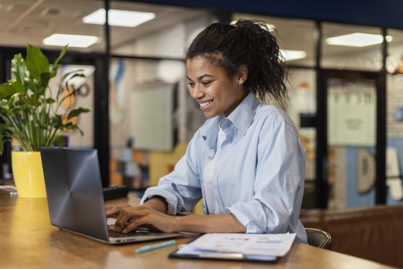 Uma mulher mexendo no computador sorrindo