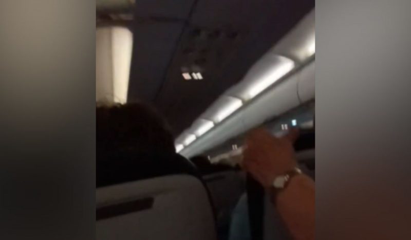 Mão de passageiro segurando assento durante turbulência em avião