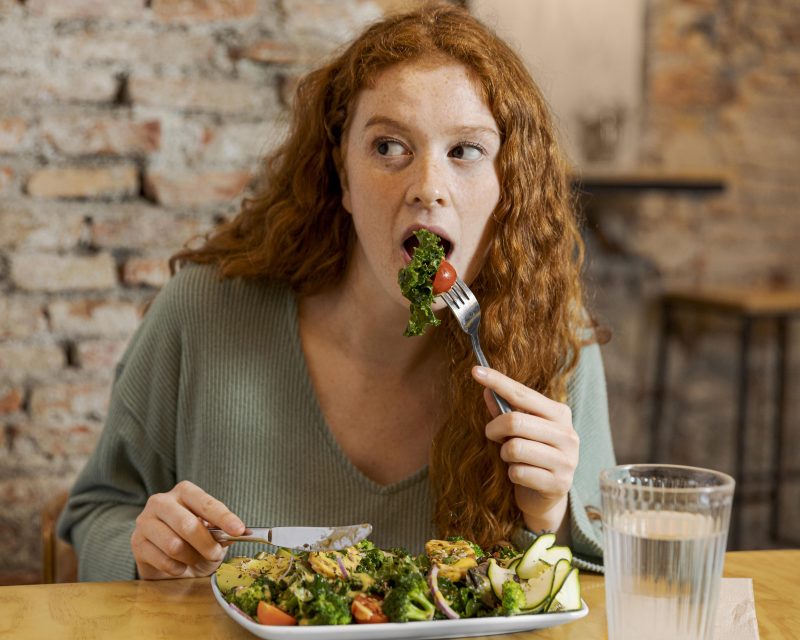 Mulher comendo um prato de salada