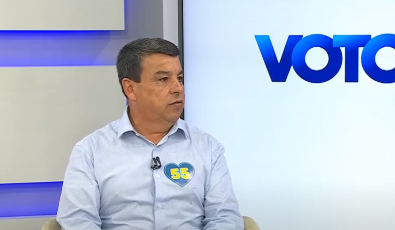 Luciano Pereira, candidato a prefeito de Palhoça - homem branco, com pele bronzeada, sentado usando camisa social azul-clara de mangas compridas