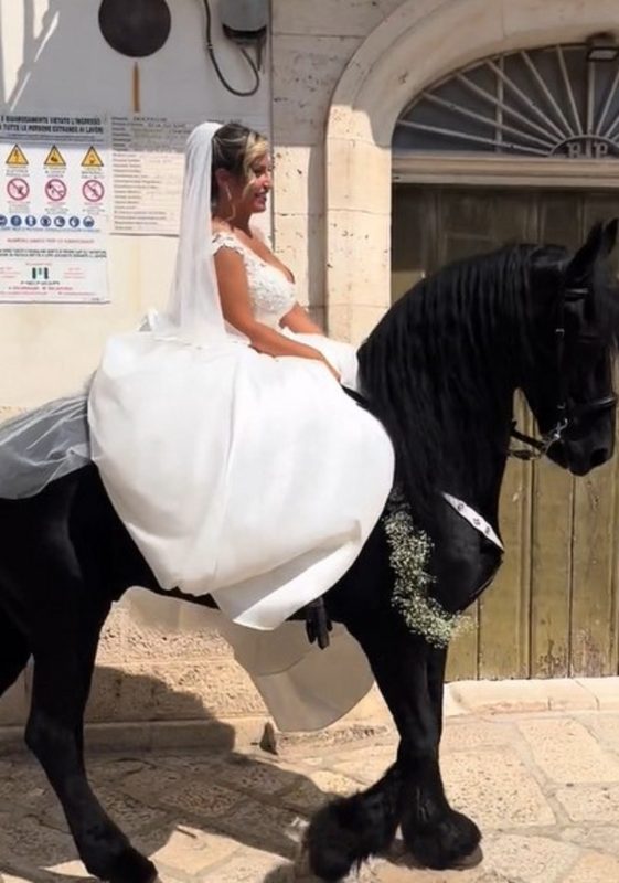 Registro da noiva montada em um cavalo chegando em seu casamento