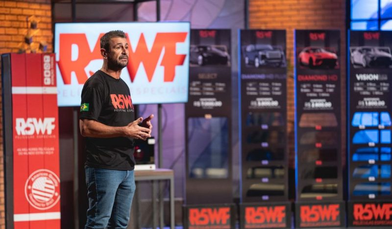 Empresário de Florianópolis - homem branco, com camisa preta, em pé apresentando empresa durante programa