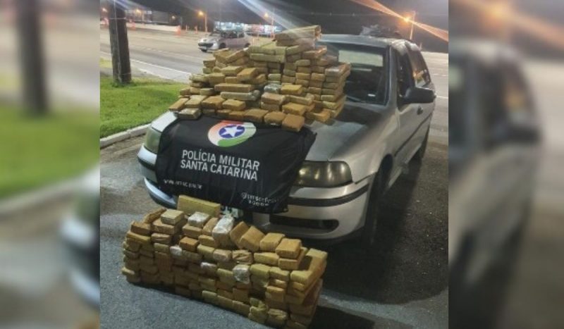 Foto mostra maconha em cima do carro utilizado para fuga em Florianópolis com a maconha apreendida e a bandeira da PMSC em cima do capô