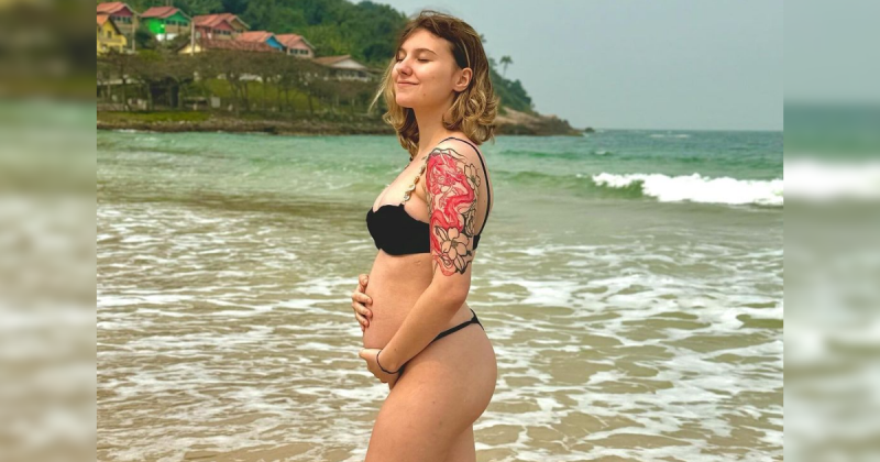 Influenciadora Isabel Veloso em praia com mão sob a barriga