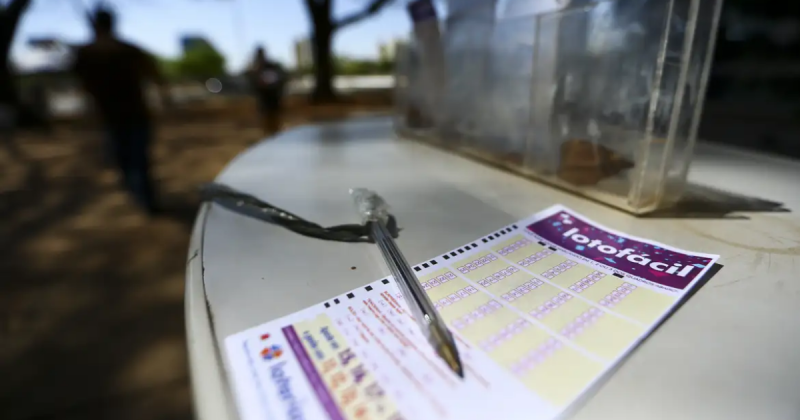 Resultado da Lotofácil hoje: volante de aposta da loteria com caneta em mesa