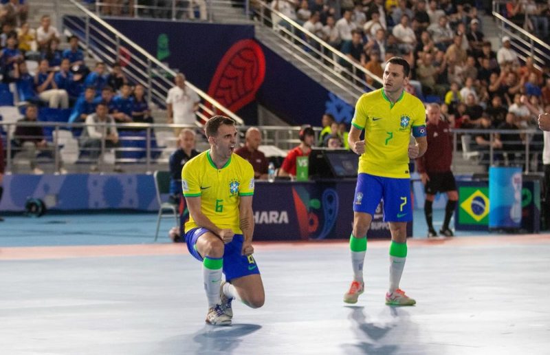 Jogadores do Brasil comemorando gol com a camisa amarela e short azul na estreia da Copa do Mundo de Futsal