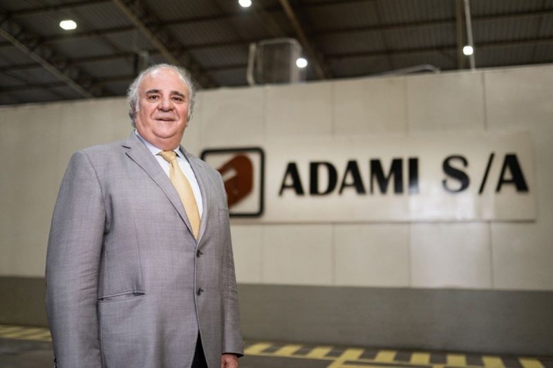 Empresário José Adami Neto em frente `logo de sua empresa