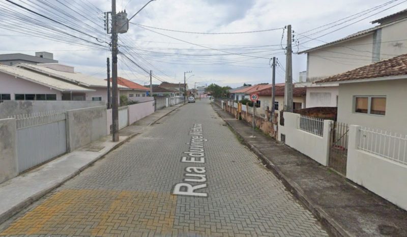 Jovem morreu com vários tiros dentro de casa localizada na rua Eduvirge Wiethorn, no bairro Barra do Aririú, foto mostra rua a luz do dia