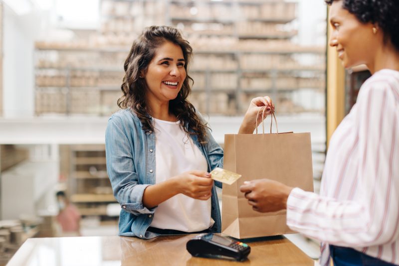 Cliente feminino feliz pagando com um cartão de crédito em uma loja de cerâmica