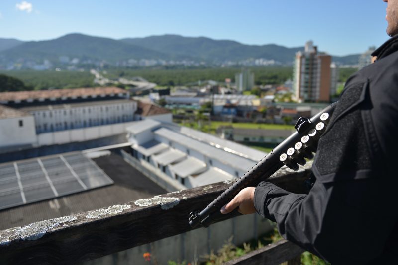 Policial segurando arma em presídio, para ilustrar as apreensões de celulares e drogas em presídios de Santa Catarina resultaram em um prejuízo de mais de R$ 6 milhões para facções