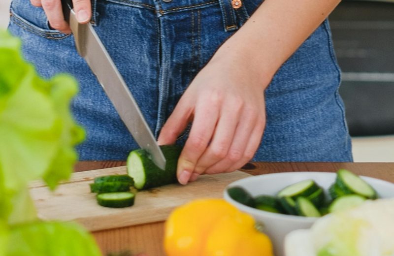 Mulher cortando um pepino em uma tábua