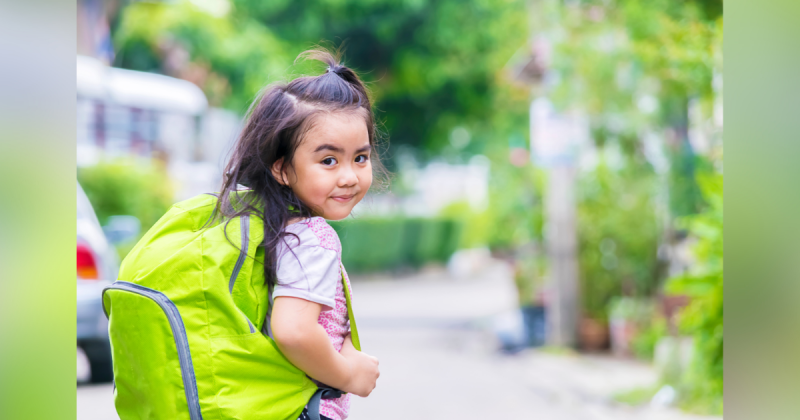 Menina criança com mochila verde nas costas