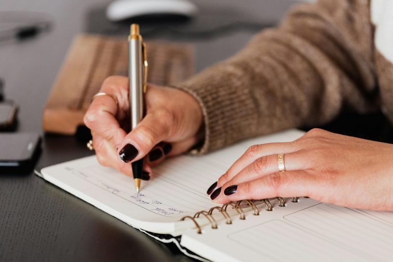 mão feminina assinando em um caderno