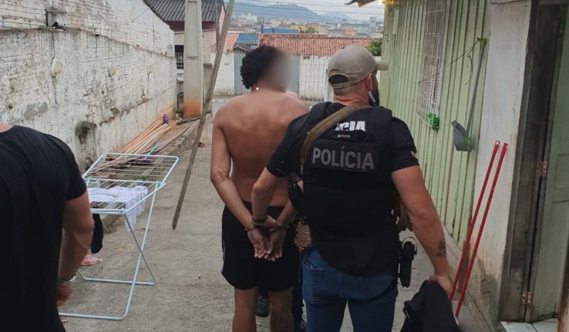 suspeito de assalto à mão armada em mercado de Florianópolis é preso por policial. Ele está de costas, sem camisa, com um calção preto