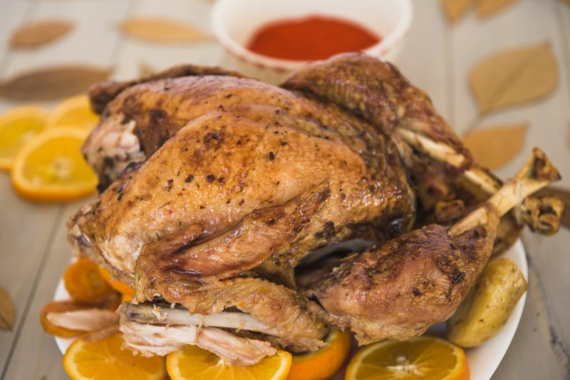 Frango assado ao lado de rodelas de laranja- veja qual o frango mais saudável 