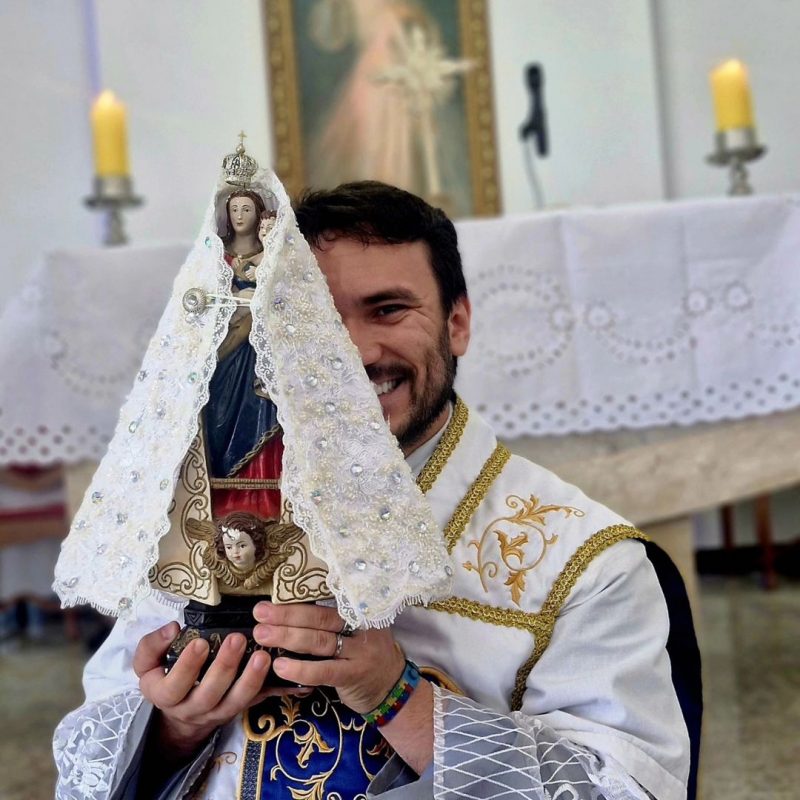 Padre Fabrício Rodrigues em uma missa, segurando imagem de santa