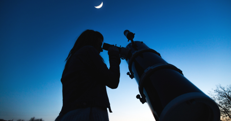 Pessoa vendo a lua por telescópio