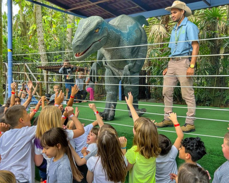 Dinossauro e funcionário durante atração para crianças em parque de Pomerode