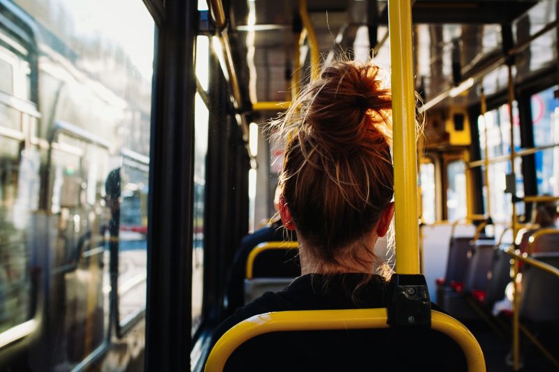 Mulher, de cabelo preso, sentada em assento de ônibus