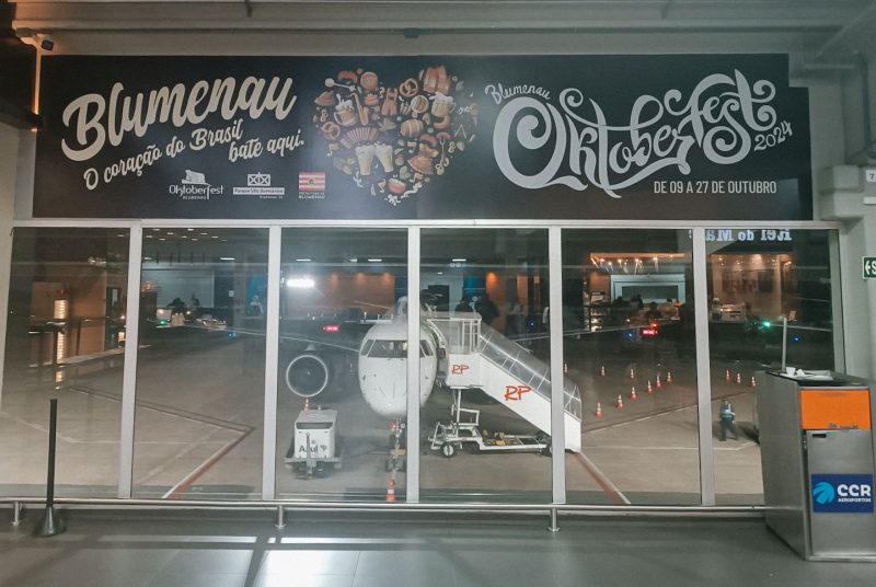 Imagem mostra avião visto de dentro do Aeroporto de Navegantes 