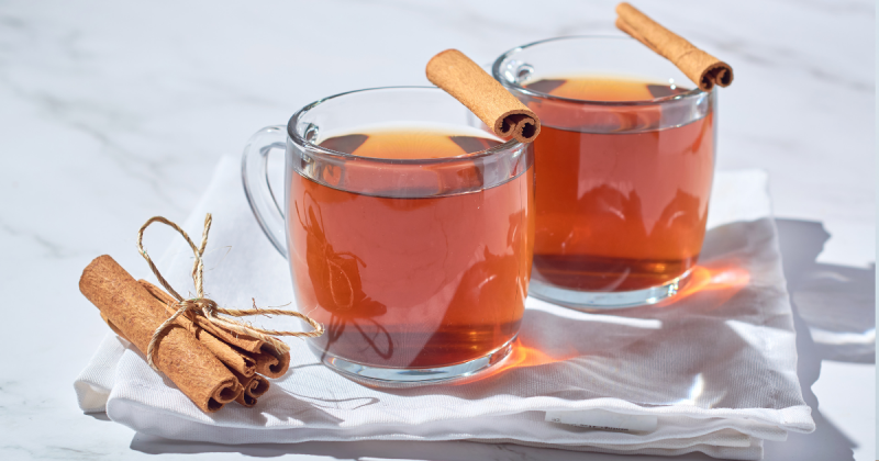 Dois copos com liquidos marrons de canelacom pauzinhos de canela