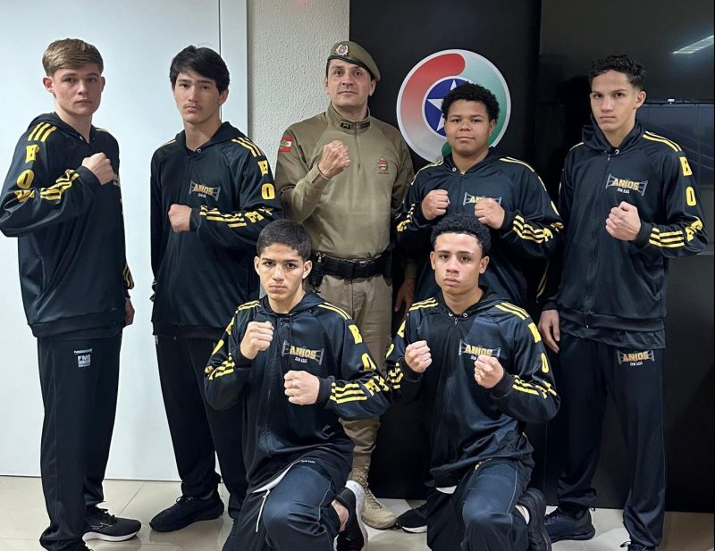 Foto mostra 6 atletas de boxe junto ao treinador da PM