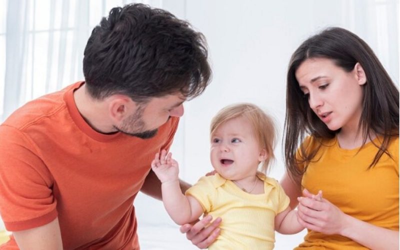 na imagem aparece o pai tentando acalmar a birra da filha que está no colo da mãe